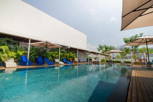 a pool at a hotel with blue chairs and umbrellas at ONOMO Hotel Abidjan in Abidjan