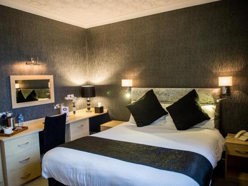 a hotel room with a large bed and a desk at Briardene Hotel in Blackpool