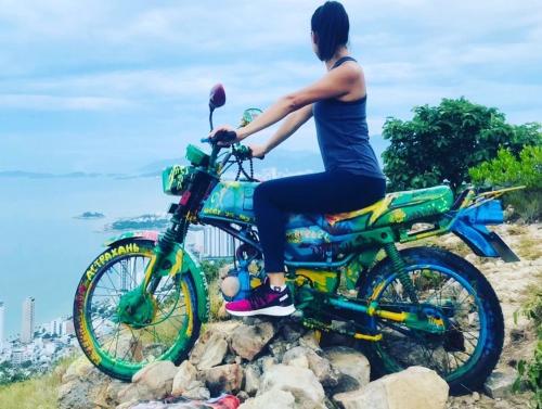 a woman sitting on a motorcycle on a hill at Bondi Backpackers Nhatrang in Nha Trang