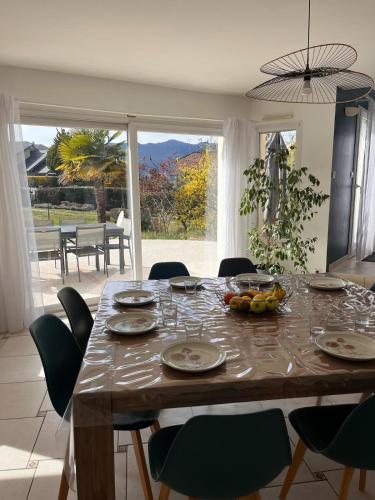 une table de salle à manger avec des chaises et une grande fenêtre dans l'établissement Maison Familiale avec piscine, à Aix-les-Bains