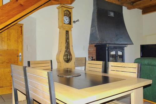 a dining room with a table and a grandfather clock at Gîte Au Cœur du Sauveterre in Le Massegros