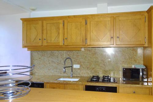a kitchen with wooden cabinets and a sink at Gîte Au Cœur du Sauveterre in Le Massegros