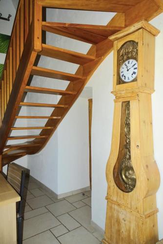 a wooden grandfather clock next to a staircase at Gîte Au Cœur du Sauveterre in Le Massegros