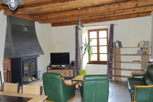 a living room with green chairs and a fireplace at Gîte Au Cœur du Sauveterre in Le Massegros