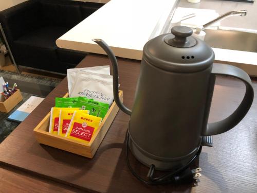 a tea kettle sitting on a desk with a box of food at Alphabed広島平和大通り in Hiroshima