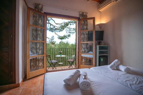 a bedroom with a bed and a balcony with a table at Finca Agroturismo Son Menut in Felanitx