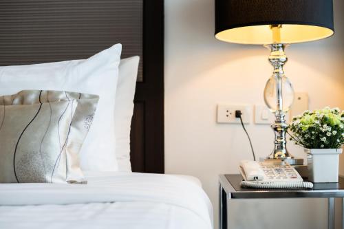 a bed with a lamp on a table with a phone at Beyond Suite in Bangkok