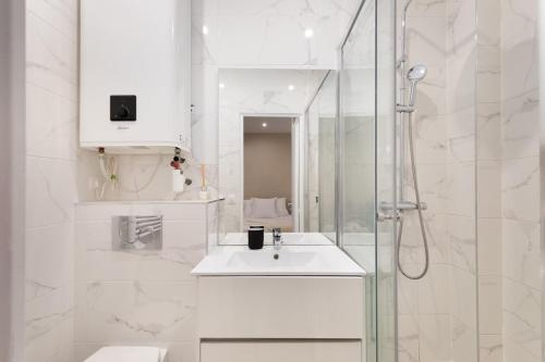 パリにあるLasuite Montbrunの洗面台とシャワー付きの白いバスルーム
