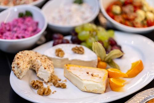 a plate of food with cheese and fruit on a table at Vitalia Seehotel in Bad Segeberg