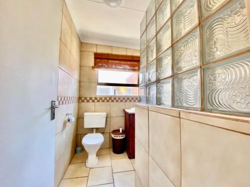 a bathroom with a toilet and a wall with tiles at Seaside Haven in Pearly Beach