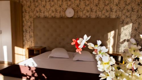 a bedroom with a bed with a large headboard and flowers at Hotel Funnytime in Bucharest