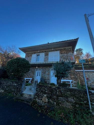 a stone house with a porch and a stone wall at Casa Paraíso in Ribeira de Pena