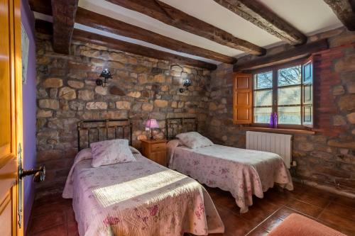 Un dormitorio con dos camas y una pared de piedra. en Apartamento Juntana 1, en Villacarriedo