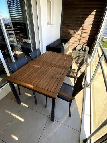 une table et des chaises en bois sur un balcon dans l'établissement Halte à Ephyra - appartement à Gruissan, à Gruissan
