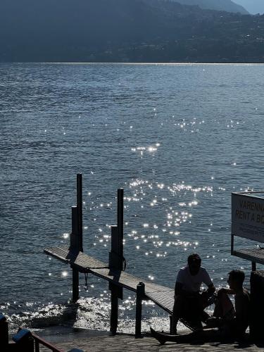a group of people sitting on a dock near the water at Postcard view 3 minutes walk from the lake in Menaggio
