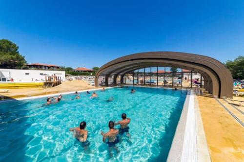 un groupe de personnes nageant dans une piscine dans l'établissement Mobilhome Le Serenité - La Plage, à Mimizan-Plage