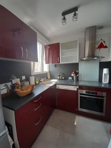 une cuisine avec des armoires rouges et un évier dans l'établissement T3 hyper centre- ascenseur- parking- balcon, à Châteauroux