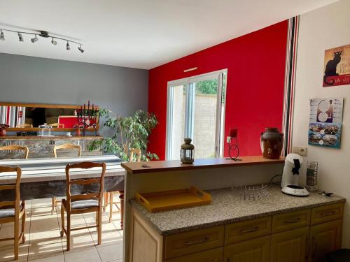 une cuisine avec des murs rouges et une table et des chaises dans l'établissement Maison 3 chb-billard-wifi-jardin-canoë, à Buzançais