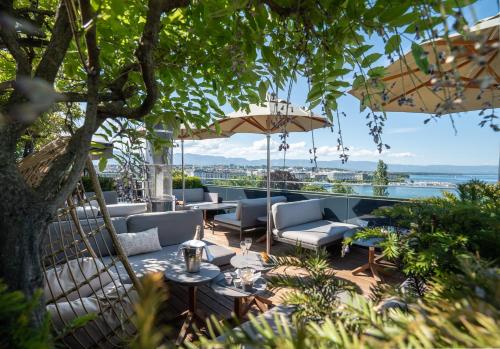 a patio with couches and tables and an umbrella at Hôtel Métropole Genève in Geneva