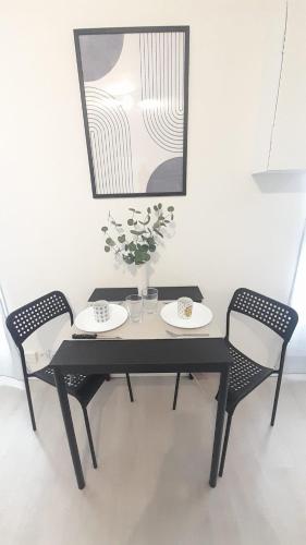 une table noire avec deux chaises et un vase avec des fleurs dans l'établissement Studio cosy Le Barangeon à Vierzon - Wifi, à Vierzon