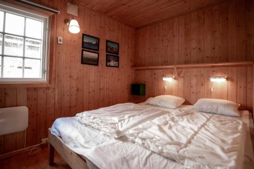 a bedroom with a white bed in a wooden wall at Trysilfjellet Nord 637 in Trysil