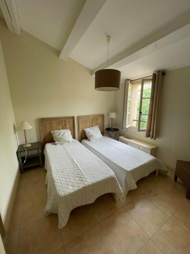 une chambre avec deux lits et une fenêtre dans l'établissement Maison Kokopetit - Dans les Corbières, à Saint-Laurent-de-la-Cabrerisse