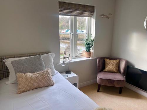 une chambre avec un lit, une chaise et une fenêtre dans l'établissement Majestic, modern & spacious harbour-view apartment with parking, à Whitby