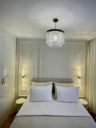 une chambre avec un grand lit blanc avec un lustre dans l'établissement Elegant Apartment Near the European Quarter, à Schiltigheim