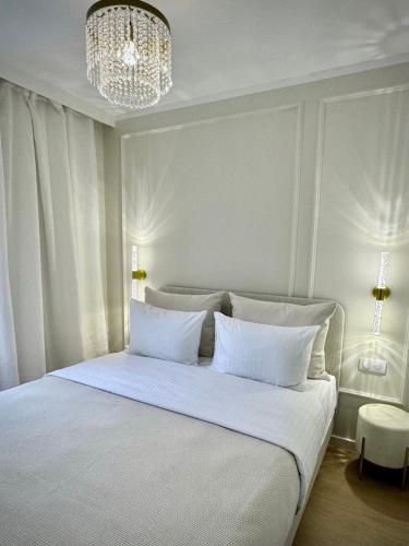 une chambre avec un grand lit blanc avec un lustre dans l'établissement Elegant Apartment Near the European Quarter, à Schiltigheim