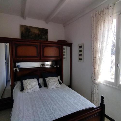 une chambre avec un lit avec une tête de lit en bois et une fenêtre dans l'établissement Le bastidon du grand chene, à Pontevès