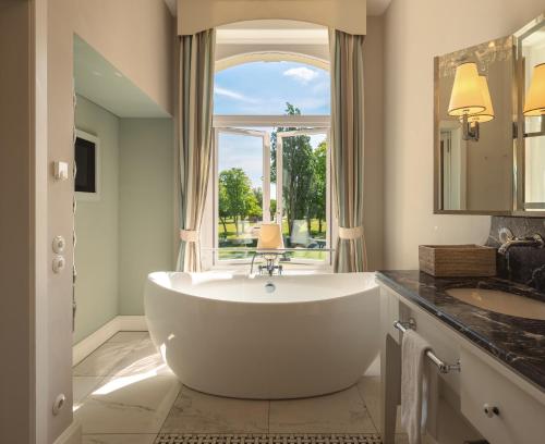 a large white tub in a bathroom with a window at Weissenhaus Private Nature Luxury Resort in Weißenhaus