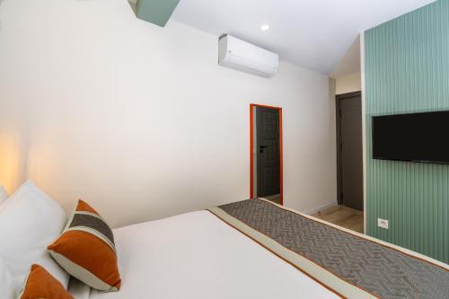 a bedroom with a white bed and a television at Echinus Lara Hotel in Antalya