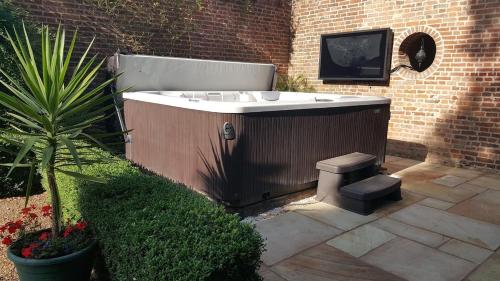 a bath tub in a garden with a tv on a brick wall at Hockwold Hall - Former Royal residence in Hockwold cum Wilton