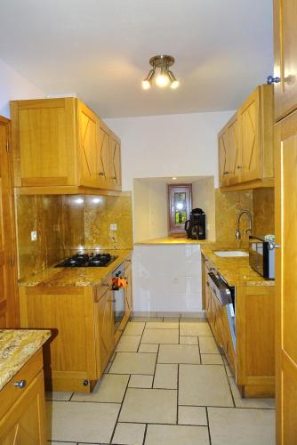 a kitchen with wooden cabinets and a tile floor at Gîte les Hortensias in Le Massegros