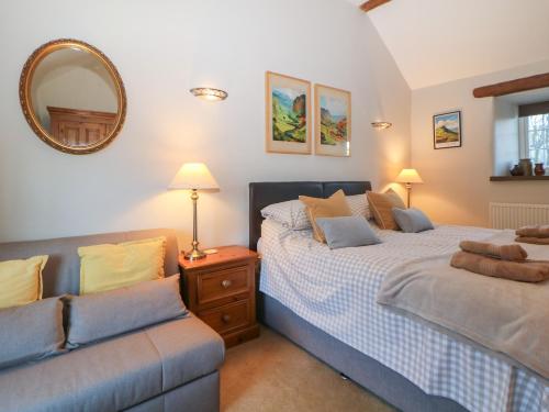 ein Schlafzimmer mit zwei Betten und einer Couch und einem Spiegel in der Unterkunft Buttercup Cottage in Castleton