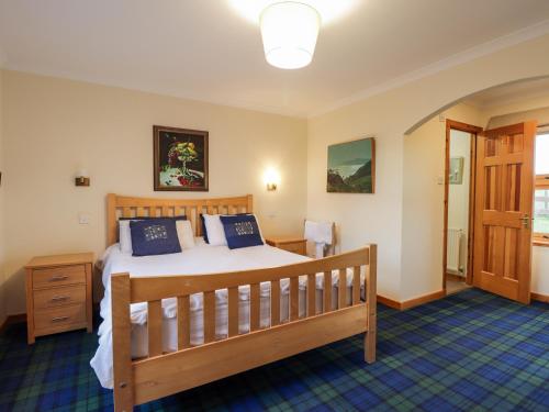 a bedroom with a wooden bed with blue pillows at Bogairn in Carron