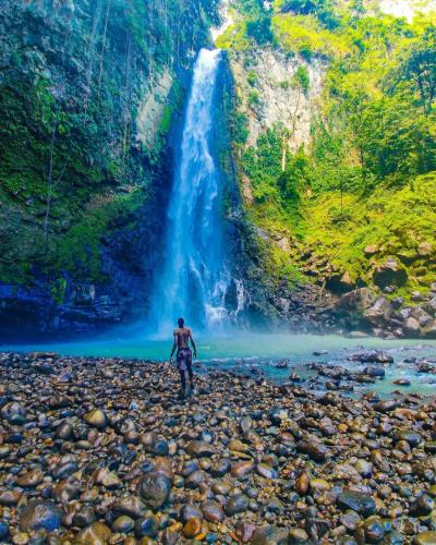 a man standing in front of a waterfall at Alexander's Place in Roseau