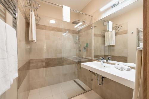 a bathroom with a sink and a glass shower at Silver Crown Hotel & Residence, Palace Quarter in Budapest