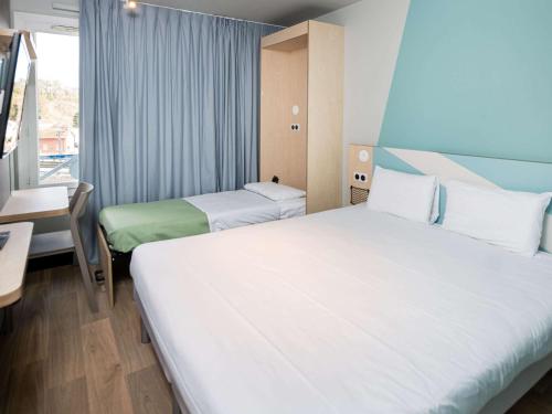 カリュイール・エ・キュイールにあるIbis Budget Lyon Caluire Cité Internationaleのベッドが2つと窓があるホテルの部屋