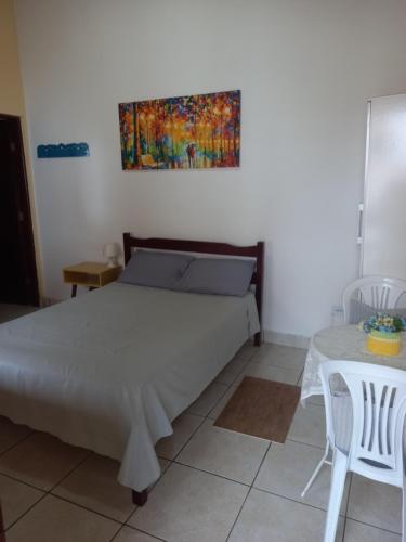 a bedroom with a bed and a painting on the wall at Maranata Suítes in Peruíbe
