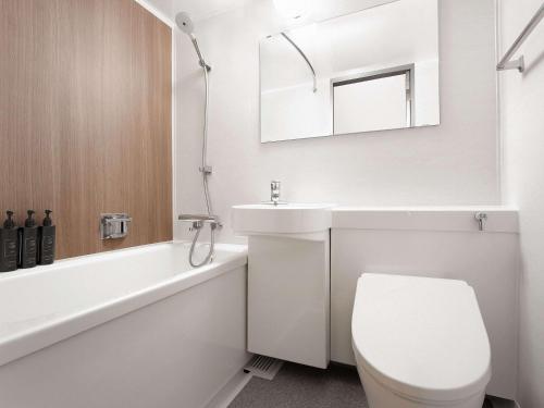 a white bathroom with a toilet and a sink at Grand Mercure Nasu Highlands Resort & Spa in Nasu