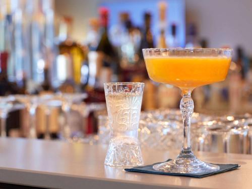 a glass of orange juice sitting on a bar at Novotel Hamburg Central Station in Hamburg