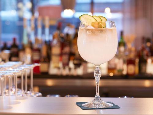a drink in a glass sitting on a bar at Novotel Hamburg Central Station in Hamburg
