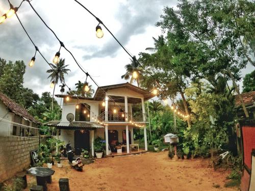 a house with lights hanging over a dirt yard at Sea Waves Home Stay in Talalla
