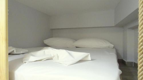 a white bed with white sheets and pillows at RelaxRooms #1 in Skala Marion