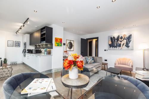 a living room with a vase of flowers on a glass table at Xylo Apartments - Kentish Town in London