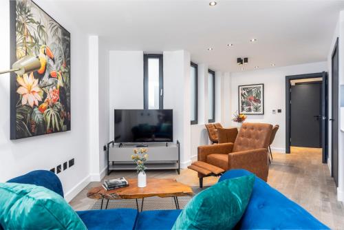 a living room with a blue couch and a tv at Xylo Apartments - Kentish Town in London