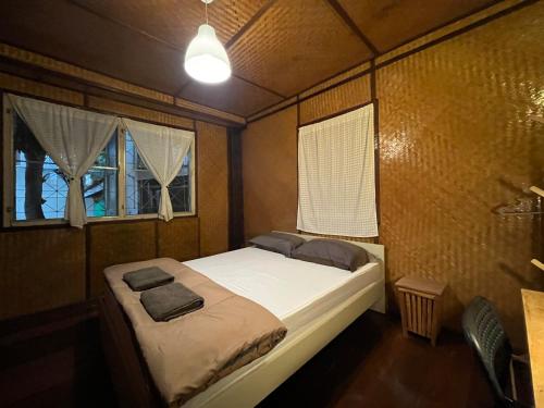 a small bedroom with a bed and two windows at Once in Lampang Guesthouse in Lampang