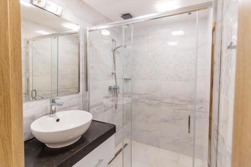 a white bathroom with a sink and a shower at Tisza Panzió és Apartman in Tiszaújváros