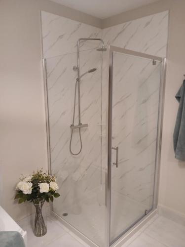 a shower in a bathroom with a vase of flowers at Home from Home in Corchoney Cross Roads